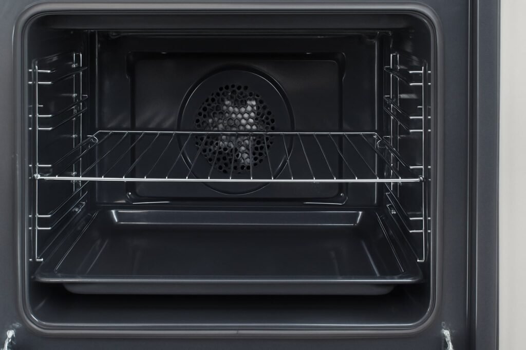 Inside view of a spotless oven with clean racks and tray after using baking soda and vinegar cleaning method